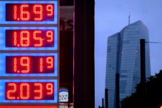 FILE - Gas prices are displayed at a gas station next to the headquarters of the European Central Bank, rear, in Frankfurt, Germany, on July 28, 2023. The inflation that has been wearing on European consumers fell sharply to 2.9% in October, its lowest in more than two years as fuel prices fell and rapid interest rate hikes from the European Central Bank took hold. (AP Photo/Michael Probst, File)