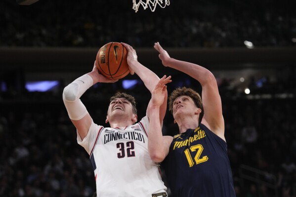 UConn center Donovan Clingan (32) goes to the basket against Marquette forward Ben Gold (12) during the first half of an NCAA college basketball game in the championship of the Big East Conference tournament, Saturday, March 16, 2024, in New York. (AP Photo/Mary Altaffer)