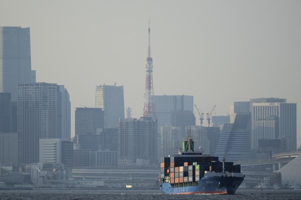Tokyo Tower is seen amid tall buildings as a container ship leaves a cargo terminal in Tokyo, Wednesday, April 9, 2025. (AP Photo/Hiro Komae)