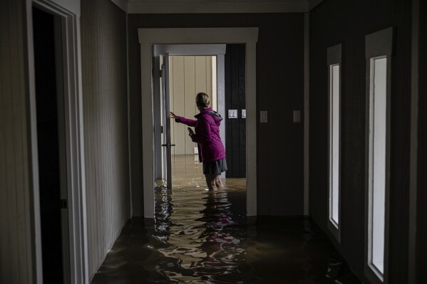 Carole Smith walks through her flooded home on Saturday, April 5, 2025, in Frankfort, Ky. (AP Photo/Jon Cherry)