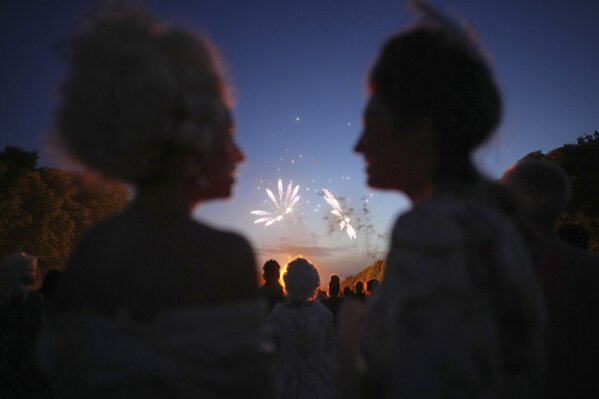 Costumed guests watch fireworks in the gardens of the Versailles castle before the Great Masked Ball in Versailles, outside Paris, Saturday, June 21, 2025. (AP Photo/Christophe Ena)
