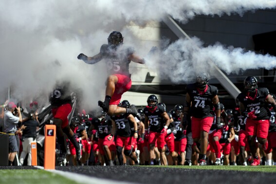 Cincinnati defensive end Justin Wodtly leaps as he takes the field with teammates before an NCAA college football game against Oklahoma, Saturday, Sept. 23, 2023, in Cincinnati. (AP Photo/Aaron Doster)