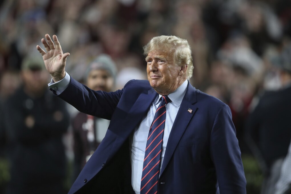 Republican presidential candidate and ormer President Donald Trump waves during halftime of an NCAA college football game between South Carolina and Clemson, Saturday, Nov. 25, 2023, in Columbia, S.C. (AP Photo/Artie Walker Jr.)