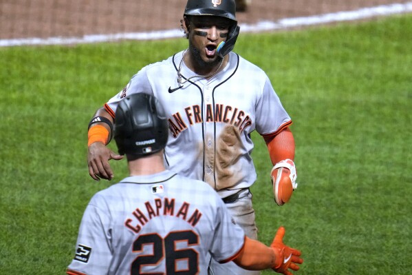 San Francisco Giants' Luis Matos, top, is greeted by Matt Chapman (26) after scoring on a single by LaMonte Wade Jr. off Pittsburgh Pirates relief pitcher Colin Holderman during the ninth inning of a baseball game in Pittsburgh, Wednesday, May 22, 2024. (AP Photo/Gene J. Puskar)