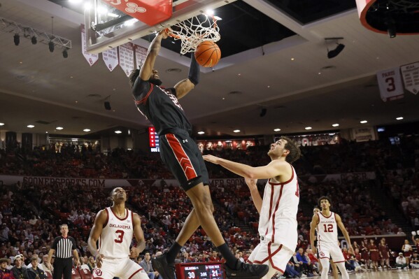 Texas Tech forward Warren Washington, center, dunks as Oklahoma guard Otega Oweh (3), forward Sam Godwin, second from right, and guard Milos Uzan (12) look on during the first half of an NCAA college basketball game, Saturday, Jan. 27, 2024, in Norman, Okla. (AP Photo/Nate Billings)