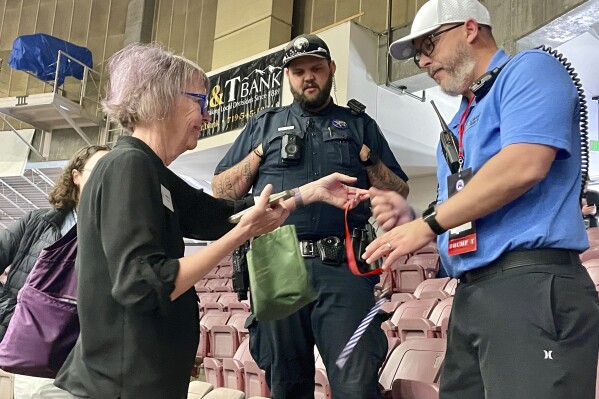 Colorado Sun reporter Sandra Fish, left, turns over media credentials to a Pueblo County sheriff's deputy and arena security staffer during the Colorado Republican Party's state assembly inside Southwest Motors Events Center on the state fairgrounds in Pueblo, Colo., on Saturday, April 6, 2024. The state GOP had Fish ejected from the event because party chairman Dave Williams said he believes the outlet's "reporting to be very unfair." (Ernest Luning/The Gazette via AP)