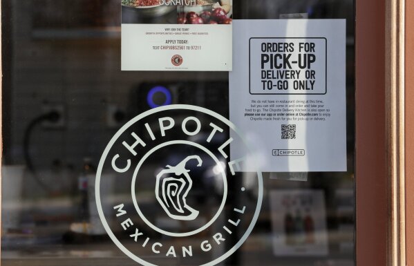 A sign hangs in the window at Chipotle Mexican Grill, Monday, March 16, 2020, in Woodmere Village, Ohio. All bars and restaurants in Ohio will be closed until further notice, said Gov. Mike DeWine, who is taking a tough stance on trying to stem the coronavirus saying "if we don't take these actions now, it'll be too late." (AP Photo/Tony Dejak)