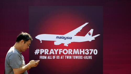 FILE - A man walks past a board reading "Pray for MH370" for passengers aboard a missing Malaysia Airlines plane, in Kuala Lumpur, Malaysia, on March 15, 2014. Malaysia's government on Thursday, June 8, 2023, condemned a Singapore-born stand-up comedian who mocked Malaysia and made fun of the 2014 disappearance of Malaysia Airlines Flight MH370 during a skit in the United States.(AP Photo/Lai Seng Sin, File)