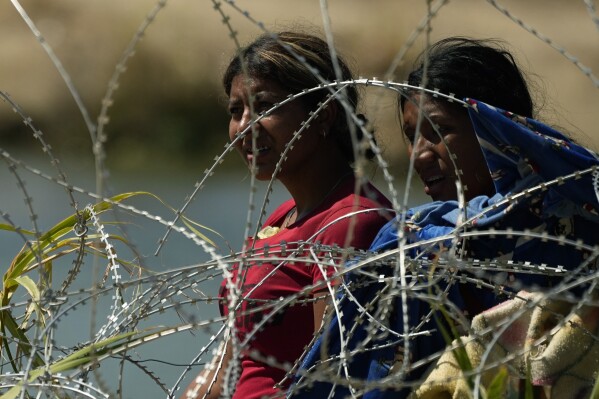 Migrante que vadearon el Río Bravo para cruzar de México a Estados Unidos se encuentran con un alambre con concertinas, o cuchillas, el 21 de septiembre de 2023, en Eagle Pass, Texas. (AP Foto/Eric Gay)