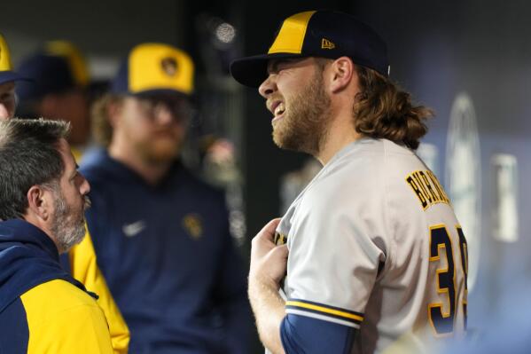 Milwaukee Brewers starting pitcher Corbin Burnes stands in the dugout as he talks with Brewers staff after leaving a baseball game against the Seattle Mariners with an apparent injury during the sixth inning Monday, April 17, 2023, in Seattle. (AP Photo/Lindsey Wasson)