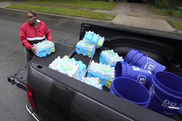 Ambie Bell, a candidate for Benton Harbor City Commissioner, delivers water to a resident Thursday, Oct. 21, 2021, in Benton Harbor, Mich. The water system in Benton Harbor has tested for elevated levels of lead for three consecutive years. Some wonder whether the problem would have been handled more quickly if Benton Harbor's residents looked more like those in neighboring St. Joseph, who are predominantly white. "Sometimes you just have to call out racism, and that's what it feels like," said Ambie Bell, helping distribute water to residents. (AP Photo/Charles Rex Arbogast)