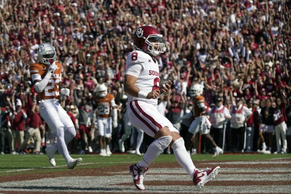 Oklahoma quarterback Dillon Gabriel (8) scores a touchdown as Texas defensive back Jahdae Barron (23) looks on during the first half of an NCAA college football game at the Cotton Bowl in Dallas, Saturday, Oct. 7, 2023. (AP Photo/LM Otero)