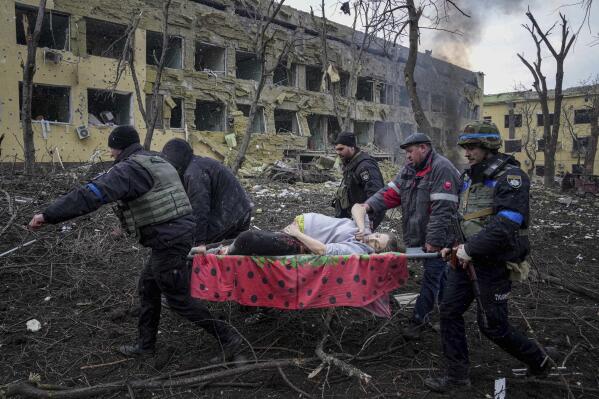 Ukrainian emergency employees and volunteers carry an injured pregnant woman from a maternity hospital damaged by shelling in Mariupol, Ukraine, Wednesday, March 9, 2022. The baby was born dead. Half an hour later, the mother died too. (AP Photo/Evgeniy Maloletka)
