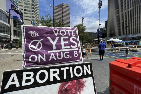 A sign asking Ohioans to vote in support of Issue 1 sits above another sign advocating against abortion rights at an event hosted by Created Equal on Thursday, July 20, 2023, in Cincinnati, Ohio. The fraught politics of abortion have helped turn an August ballot question in Ohio that would make it harder to change the state constitution into a cauldron of misinformation, fear-mongering and vitriol. (AP Photo/Patrick Orsagos)
