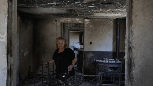 Retiree Chrysoula Renieri visits her burned out home in Loutraki, about 82 kilometres (51 miles) west of Athens, Greece, Thursday, July 20, 2023. Renieri, 72, was among dozens of people who lost their home in the area as wildfires tore through hillside scrub and forests outside Athens. (AP Photo/Thanassis Stavrakis)