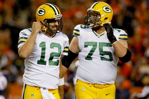 FILE - Green Bay Packers quarterback Aaron Rodgers (12) leaves the field with tackle Bryan Bulaga (75) during the team's NFL football game against the Denver Broncos, Nov. 1, 2015, in Denver. Bulaga plans to retire from the NFL with the Packers after spending the first 10 seasons of his career with them. Packers general manager Brian Gutekunst announced Thursday, Nov. 16, 2023, that Bulaga had let the team know about his intent to retire as a Packer. Bulaga hasn’t played in the NFL since appearing in one game with the Los Angeles Chargers in 2021. (AP Photo/Joe Mahoney, File)