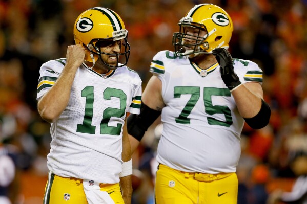 FILE - Green Bay Packers quarterback Aaron Rodgers (12) leaves the field with tackle Bryan Bulaga (75) during the team's NFL football game against the Denver Broncos, Nov. 1, 2015, in Denver. Bulaga plans to retire from the NFL with the Packers after spending the first 10 seasons of his career with them. Packers general manager Brian Gutekunst announced Thursday, Nov. 16, 2023, that Bulaga had let the team know about his intent to retire as a Packer. Bulaga hasn’t played in the NFL since appearing in one game with the Los Angeles Chargers in 2021. (AP Photo/Joe Mahoney, File)
