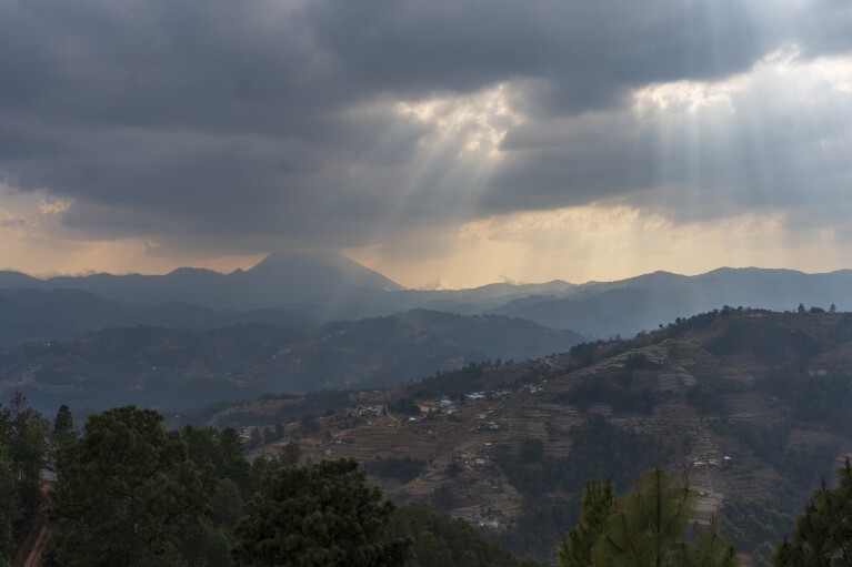 The sun is partially covered by clouds in Comitancillo, Guatemala, Monday, March 18, 2024. In this small town, nearly two dozen local migrants have died in recent mass tragedies: either asphyxiated in the trailer in San Antonio, Texas, in June 2022 or shot and set afire by rogue police officers in Camargo, Mexico, in January 2021. (AP Photo/Moises Castillo)
