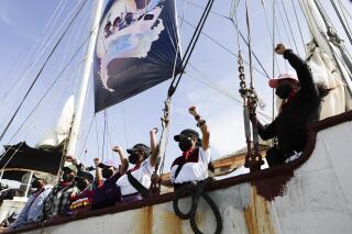 A delegation of the Zapatista Army of National Liberation, EZLN, say goodbye from a ship as they depart to Europe from Isla Mujeres, Quintana Roo state, Mexico, Sunday, May 2, 2021. The rebel delegation says they are planning the trip to "invade" Spain, as Mexico marks the anniversary of its 1519-1521 Spanish Conquest. (AP Photo/Eduardo Verdugo)