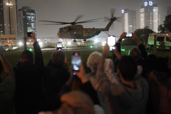 Eine Gruppe Israelis beobachtet einen Hubschrauber mit aus dem Gazastreifen befreiten Geiseln auf dem Hubschrauberlandeplatz des Schneider Children's Medical Center in Peta Tikva, Israel, Sonntag, 26. November 2023.  (AP Photo/Leo Correa)