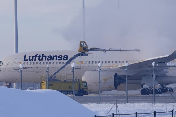 A Lufthansa aircraft is de-iced at the airport in Munich, Germany, Tuesday, Dec. 5, 2023.Munich Airport temporarily suspended flight operations on Tuesday morning due to freezing rain as cold weather continued in the region. (AP Photo/Matthias Schrader)