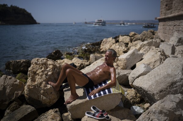 FILE - A man sunbathes in high temperatures in Marseille, southern France, Aug. 19, 2023. UN weather agency says Earth sweltered through the hottest summer ever as record heat in August capped a brutal, deadly three months in northern hemisphere. (AP Photo/Daniel Cole, File)