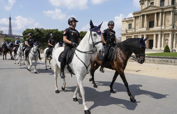 FILE - Mounted Portuguese, Spanish and French police ride during a security presentation during the 2024 Summer Olympics, in Paris, France, Friday, Aug. 2, 2024. The Eiffel Tower is seen at left in the background. (AP Photo/Michel Euler, File)
