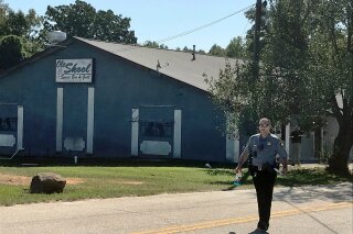 A Lancaster County Sheriff's deputy walks around the Old Skool Sports Bar and Grill, the scene of a shooting early in the morning, north of Lancaster, S.C. on Saturday, Sept. 21, 2019.  Lancaster County Sherriff's Office said in a statement that the agency was investigating a fatal shooting that also injured several people.  (Jessica Holdman/The Post And Courier via AP)