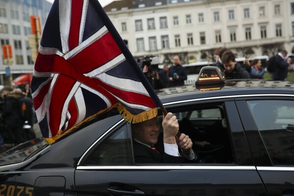 British MEP Jonathan Bullock holds an Union flag as he leaves with other party members the European Parliament in Brussels to take the Eurostar train back to Britain, Friday, Jan. 31, 2020. The U.K. is due to leave the EU on Friday the first nation in the bloc to do so. (AP Photo/Francisco Seco)