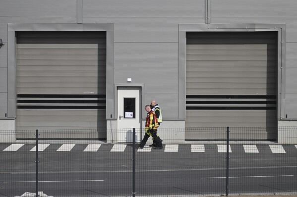 Fire department employees walk outside the Tesla car factory after production came to a standstill and workers were evacuated following a power outage, in Grünheide, Germany, Tuesday, March 5, 2024. (Sebastian Gollnow/dpa via AP)