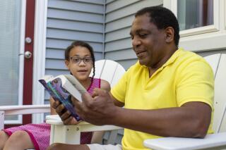 Andrew Grant-Thomas reads to his daughter, Lena Grant-Giraud, on the back porch at their home in Amherst, Mass., on Monday, May 24, 2021. Grant-Thomas and his wife, Melissa Giraud, started the nonprofit EmbraceRace in 2016 when they found few resources to help them talk with their young daughters about race. The nonprofit’s approach, Grant-Thomas says, can be summed up in a simple mantra: “Start young, and keep going.” (M. Scott Brauer/Chronicle of Philanthropy via AP)