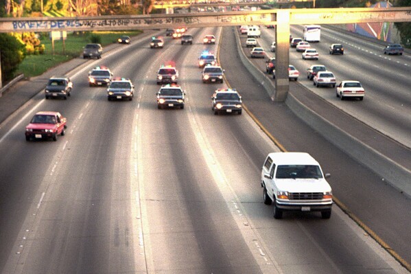 FILE - In this June 17, 1994, file photo, a white Ford Bronco, driven by Al Cowlings carrying O.J. Simpson, is trailed by Los Angeles police cars as it travels on a freeway in Los Angeles. Simpson, the decorated football superstar and Hollywood actor who was acquitted of charges he killed his former wife and her friend but later found liable in a separate civil trial, has died. He was 76. (AP Photo/Joseph Villarin, File)