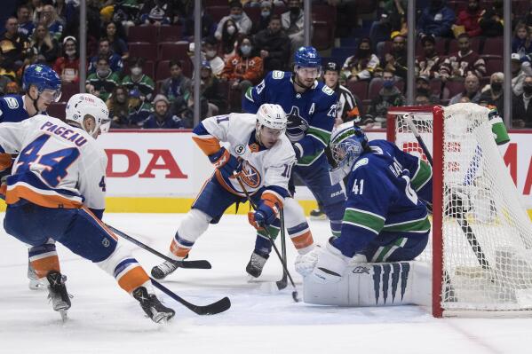 New York Islanders' Zach Parise (11) scores against Vancouver Canucks goalie Jaroslav Halak (41) as Canucks' Oliver Ekman-Larsson (23) watches during the first period of an NHL hockey game Wednesday, Feb. 9, 2022, in Vancouver, British Columbia. (Darryl Dyck/The Canadian Press via AP)