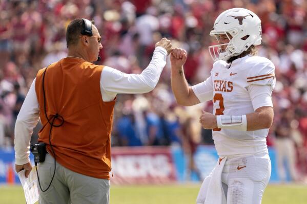 Texas quarterback Quinn Ewers (3) is congratulated by head coach Steve Sarkisian after a touchdown during the second half of an NCAA college football game against Oklahoma at the Cotton Bowl, Saturday, Oct. 8, 2022, in Dallas. Texas won 49-0. (AP Photo/Jeffrey McWhorter)