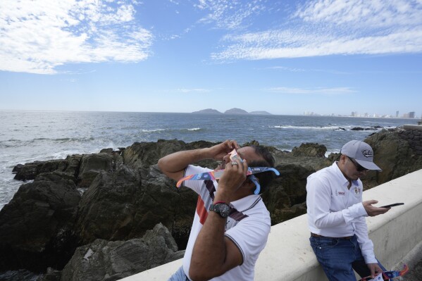 A man tests special glasses in preparation for viewing an upcoming solar total eclipse in Mazatlan, Mexico, on Sunday, April 7, 2024. (AP Photo/Fernando Llano)