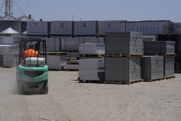 A worker drives a fork lift near rows of used solar panels as they begin the recycling process at We Recycle Solar on Tuesday, June 6, 2023, in Yuma, Ariz. (AP Photo/Gregory Bull)