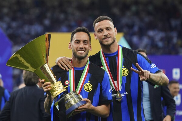Inter's Hakan Calhanoglu and Mirko Arnautovic celebrate their victory of the "scudetto" after the Serie A soccer match between Inter and Lazio at the San Siro Stadium in Milan, Italy, Sunday, May 19, 2024. (Spada/LaPresse via AP)