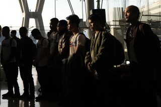 Rehenes tailandeses que fueron liberados por Hamás guardan un minuto de silencio a su llegada al Aeropuerto Internacional Suvarnabhumi, en la provincia de Samut Prakarn, Tailandia, el jueves 30 de noviembre de 2023. (AP Foto/Sakchai Lalit)