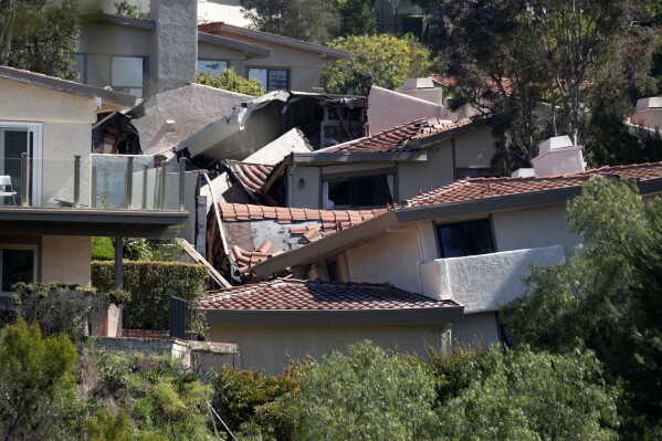 Damaged homes are torn apart by earth movement in the Los Angeles County city of Rolling Hills Estates, Calif., on Monday, July 10, 2023. The dozen homes torn apart were hastily evacuated by firefighters Saturday when cracks began appearing in structures and the ground. (AP Photo/Richard Vogel)