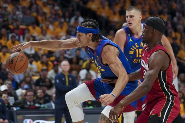 Denver Nuggets forward Aaron Gordon, left, maintains possession of the ball while defended by Miami Heat forward Jimmy Butler, right, during the first half of Game 1 of basketball's NBA Finals, Thursday, June 1, 2023, in Denver. (AP Photo/Jack Dempsey)