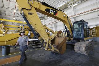 FILE - A Puckett Machinery Company technician walks past a new heavy duty Caterpillar excavator that awaits modification at Puckett Machinery Company in Flowood, Miss. Sept. 18, 2019. Caterpillar continued to see a healthy surge in sales during its fourth quarter of 2022, as the economy strengthens. Sales climbed 23% to $13.8 billion. (AP Photo/Rogelio V. Solis)