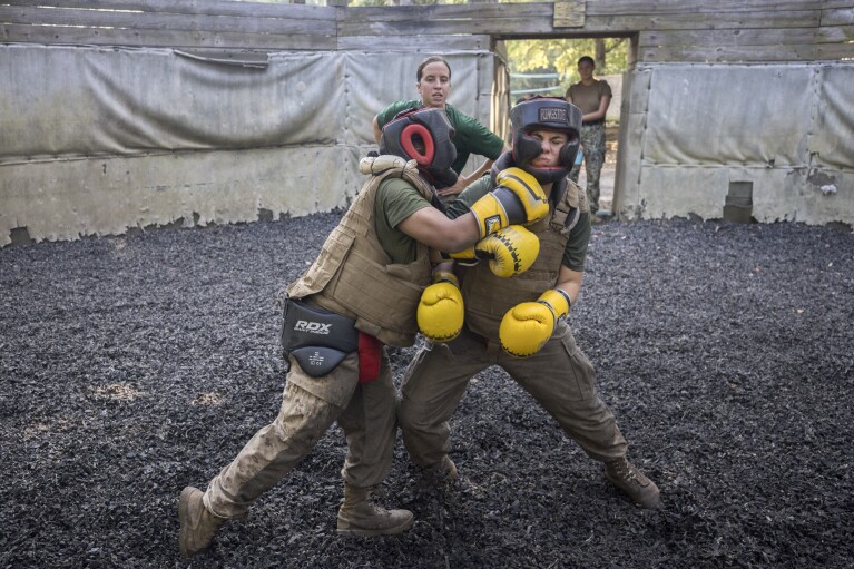 U.S. Marine Corps martial arts instructor Sgt. Micah Shull, center, trains two female recruits during a hand-to-hand combat drill during a portion of training known as the Crucible at the Marine Corps Recruit Depot, Thursday, June 29, 2023, in Parris Island, S.C. (AP Photo/Stephen B. Morton)