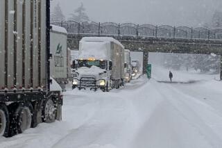 In this photo provided by the Oregon Department of Transportation, trucks are parked in the snow along Interstate 84 in the Columbia River Gorge about 60 miles east of Portland, Ore., Monday, Jan. 3, 2022. Heavy snow and high winds forced officials to close dozens of state roads in eastern Oregon on Monday and Interstate 84 was shut down through the Columbia River Gorge, while blowing snow also closed a major road over the Cascade Mountains in Washington. (Oregon Department of Transportation via AP)