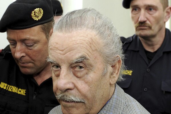 FILE - Josef Fritzl, center, is escorted to the fourth day of his trial in the provincial courthouse in St. Poelten, Austria, Thursday, March 19, 2009. An Austrian court has ruled that the man who kept his daughter captive for 24 years and raped her thousands of times, fathering seven children with her, can be moved from psychiatric detention to a regular prison. The decision follows a legal back-and-forth on Josef Fritzl's future. (AP Photo/Robert Jaeger, Pool, File)
