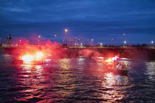 French fishermen light flares as they block the entrance to the port of Saint-Malo, western France, Friday, Nov. 26, 2021. French fishing crews are threatening to block French ports and traffic under the English Channel on Friday to disrupt the flow of goods to the U.K., in a dispute over post-Brexit fishing licenses. (AP Photo/Jeremias Gonzalez)
