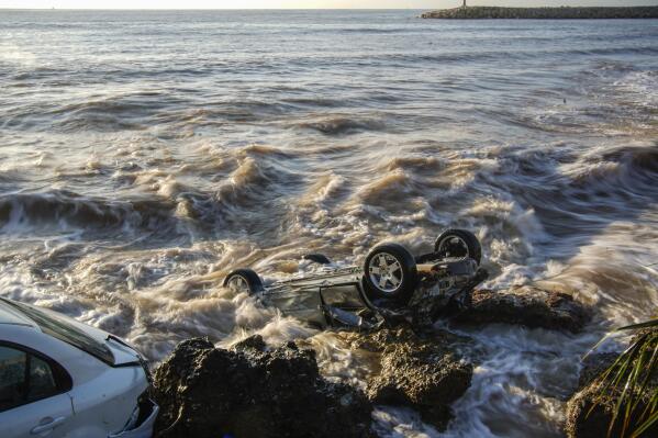 Wrecked cars stuck in the rocky shore of the seaside town of Alcanar, in northeastern Spain, Thursday, Sept. 2, 2021. A downpour Wednesday created flash floods that swept cars down streets in the Catalan town of Alcanar. Most of mainland Spain is under alert for heavy rains. (AP Photo/Joan Mateu Parra)