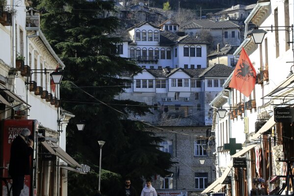 Two men walk in Gjirokastra town, southern Albania, Friday, Feb. 5, 2021. Tourism had been flourishing in the UNESCO-protected city of Gjirokastra but the coronavirus pandemic brought an abrupt halt to that, with the prospects still bleak in 2021, and now residents are calling for government help to keep their businesses afloat. (AP Photo/Hektor Pustina)