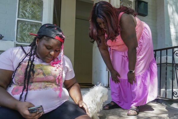 Nikuya Brooks stands on the porch at home with her 16-year-old daughter Gabrielle Jones, left, and their dog Snowball Friday, Aug. 11, 2023, in Chicago. Brooks' bond was set at $150,000 after her first-time arrest on drug charges in 2017, according to the mother of three. No one in her family could pull together 10% of the bond for her to walk free. Illinois will become the first state to completely abolish cash bail on Sept. 18, making the state a testing ground for whether and how eliminating it works on a large scale. (AP Photo Erin Hooley)
