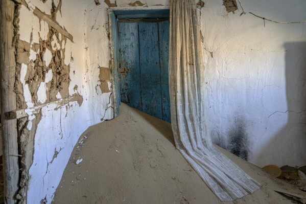 A house decimated by sandstorms sits in the destroyed village on the edge of the dried-up Aral Sea, near Tastubek, Kazakhstan, Monday, July 3, 2023. The hazardous conditions around the Aral include toxic dust storms, towns that are swallowed by dunes, water salination and evaporation, drier winters and hotter summers. (AP Photo/Ebrahim Noroozi)