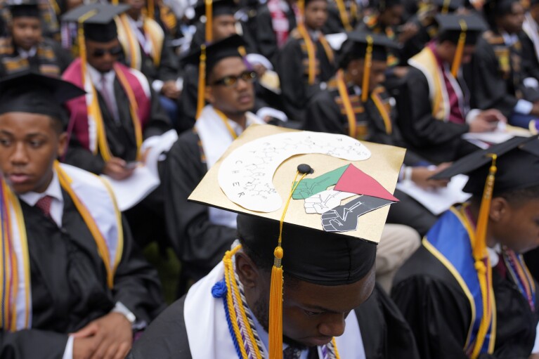 Valedictorian DeAngelo Jeremiah Fletcher shows his mortarboard with a protest image representing a Palestinian flag as President Joe Biden speaks to graduating students at the Morehouse College commencement Sunday, May 19, 2024, in Atlanta. (AP Photo/Alex Brandon)
